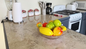 A kitchen counter with a bowl of fruit, a blender, a coffee maker, and a stove. - Peaceful 2BR/1BA modern home, perfect for a laid-back Caribbean getaway (Gros Islet)