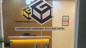 La entrada al Hotel Boutique Gardenia Lakewood, con una recepción, una puerta de cristal y un cartel arriba.