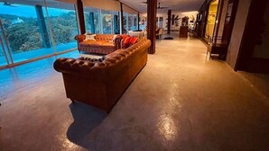 A spacious living area with a large leather sofa, a dining table, and a view of the outdoors.