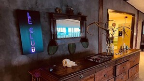 A wooden dresser with drawers, a mirror above it, and a neon sign on the wall.