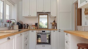 Een moderne keuken met witte kastjes, een ingebouwde oven en een houten aanrecht.