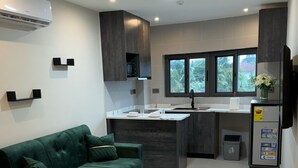 Une cuisine moderne avec un îlot central, des meubles de couleur sombre et un canapé vert.