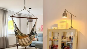 Une pièce avec un fauteuil en forme de hamac, un meuble vitré contenant des collations et une lampe sur une table.