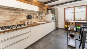 Une cuisine moderne équipée d’une cuisinière à gaz, d’un four et d’un four à micro-ondes, avec des éléments décoratifs en bois et un coin repas comprenant des chaises.
