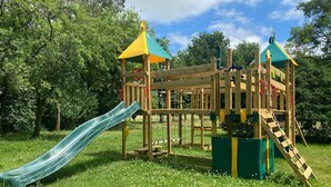 A wooden playground structure with a slide, climbing net, and platforms. - Gite 2 in the heart of the countryside (Chimay)