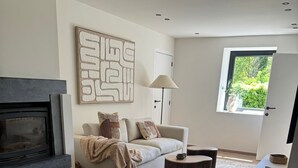 A modern living room with a fireplace, a sofa, a coffee table, and a side table. - Gite 2 in the heart of the countryside (Chimay)