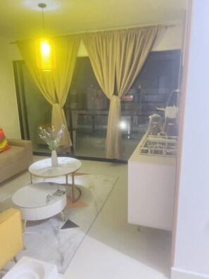 A living room with a sofa, a coffee table, and a dining area with a kitchen counter.