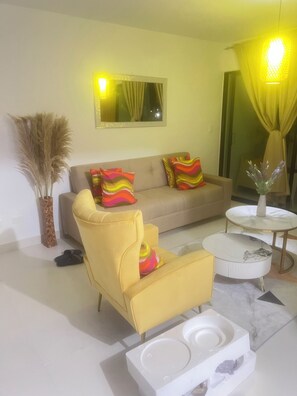 Una sala de estar con sofá, sillón, mesa de centro y plantas decorativas.
