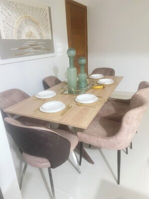 A dining area with a wooden table, six chairs, and a decorative wall piece.