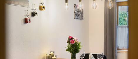 Un'area pranzo con tavolo in legno, sedie, un vaso di fiori, candele e lampade a sospensione.