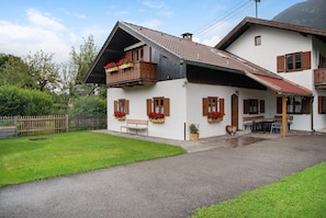 A two-story house with a balcony, a wooden fence, and a paved driveway.