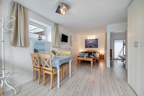 Une pièce comprenant une table à manger, des chaises, un canapé, un téléviseur et un tableau accroché au mur.