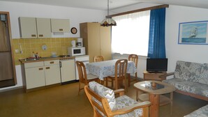 Een ruimtelijke woonkamer met een keuken, eethoek en zithoek.