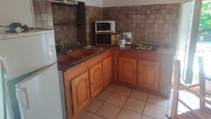 A compact kitchen with wooden cabinets, a refrigerator, a microwave, and a coffee maker.