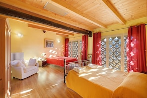 A room with a bed, a sofa, and a window with patterned curtains.