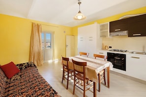 A compact living space with a dining area, kitchenette, and a sofa with a patterned cover.