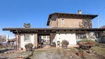 Ein zweistöckiges Haus mit Terrasse, Blumentöpfen und einer Schubkarre.