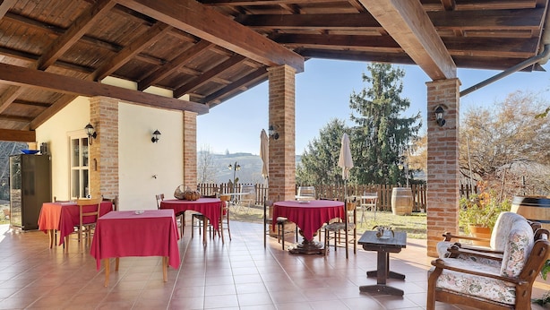 An outdoor patio with tables and chairs, a wooden bench, and a brick wall.