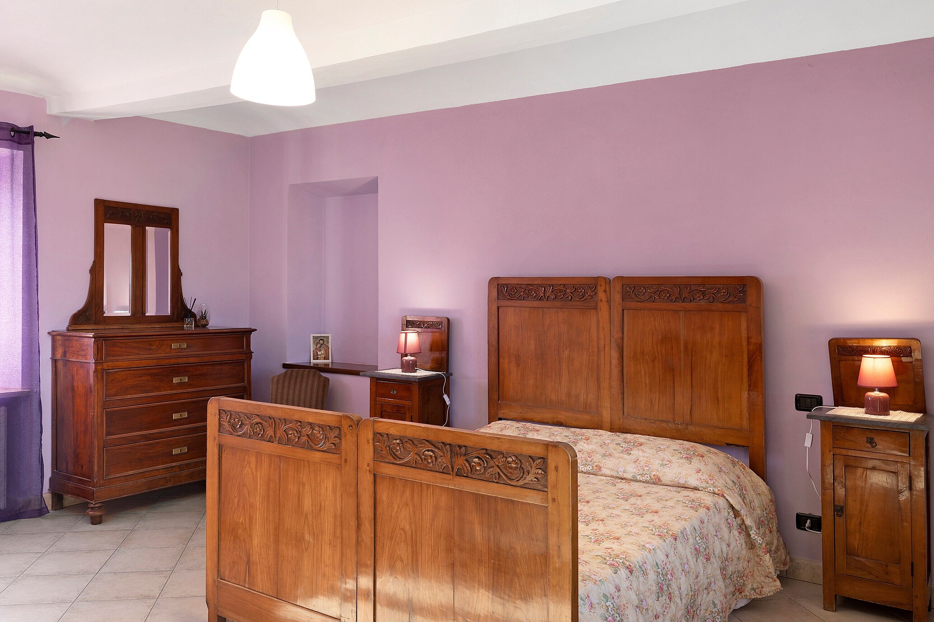 Ein Schlafzimmer mit einem hölzernen Bett, einem Schminktisch und einem Nachttisch, alle mit aufwendigen Verzierungen.