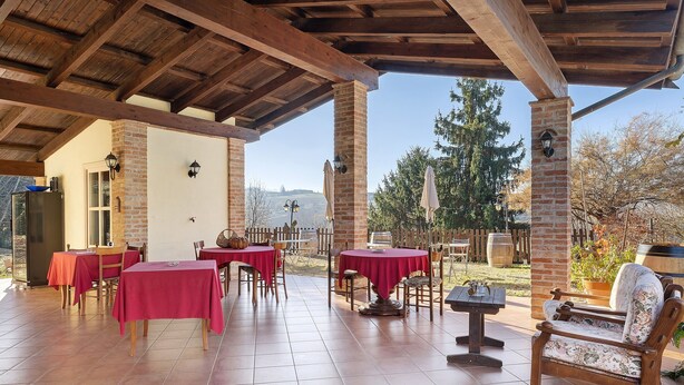 Un patio exterior con mesas y sillas, un banco de madera y una pared de ladrillo.