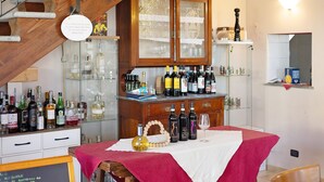 Una habitación con una escalera de madera, un armario con botellas de vino y una mesa con mantel rojo.