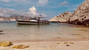 Een boot op kalm water, met rotsachtige kliffen op de achtergrond.