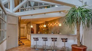 Een modern interieur met een centrale bar, meerdere hangende pendellampen en een grote potplant.