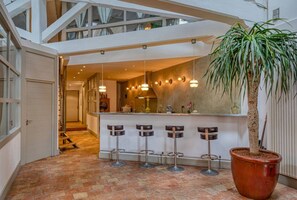 A modern interior with a central bar area, multiple hanging pendant lights, and a large potted plant. - Grand Loft - Centre-ville - Bateau à la location (Marseille)