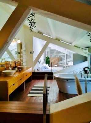 A modern bathroom with a wooden vanity, a large bathtub, and a view of a bedroom through a skylight. - Grand Loft - Centre-ville - Bateau à la location (Marseille)