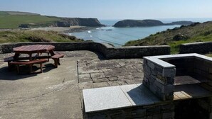A coastal view with a picnic table and stone seating area. - The Creamery at Annestown House (Tramore)