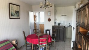 Een eethoek met een rode tafelkleed, houten stoelen en een vintage radio.