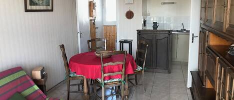 Un comedor con mantel rojo, sillas de madera y una radio antigua.