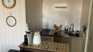 Een kleine keuken met een klok, een koffiezetapparaat, een waterkoker en een spoelbak.