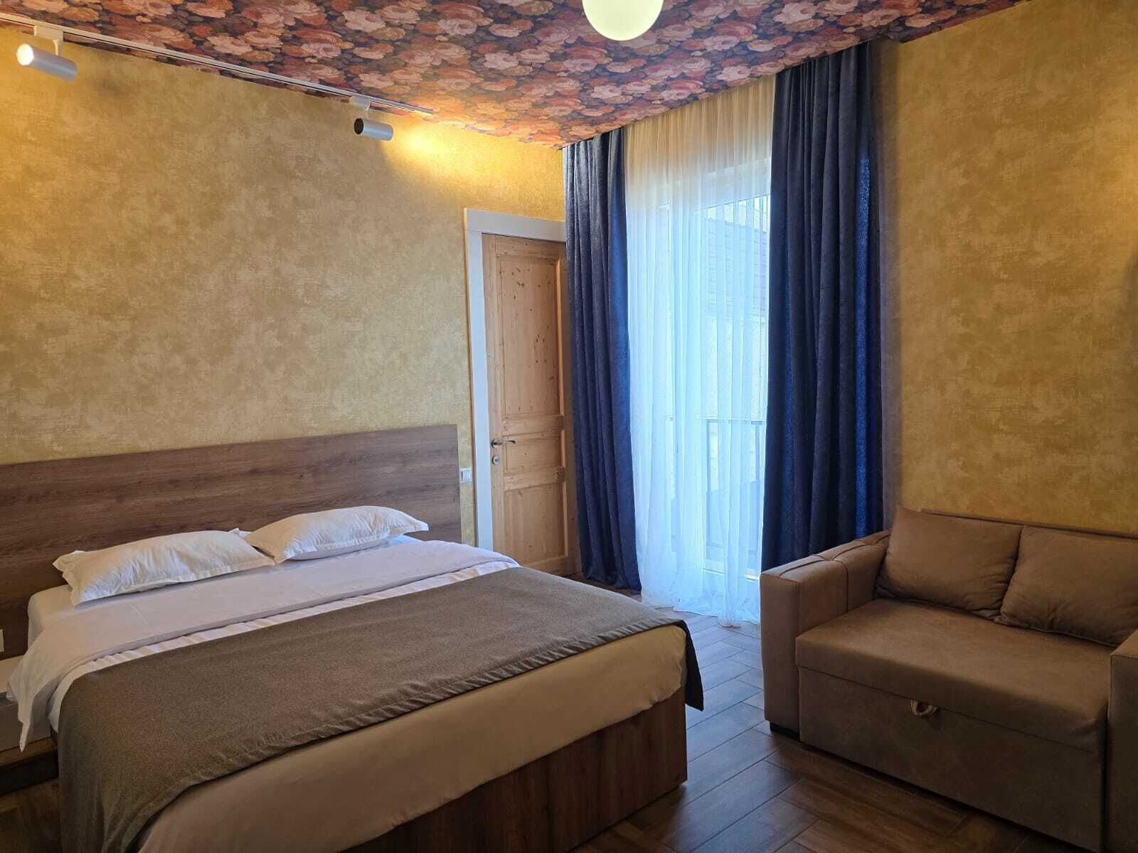 Une chambre d’hôtel avec un lit, un canapé, une porte et une fenêtre avec des rideaux.