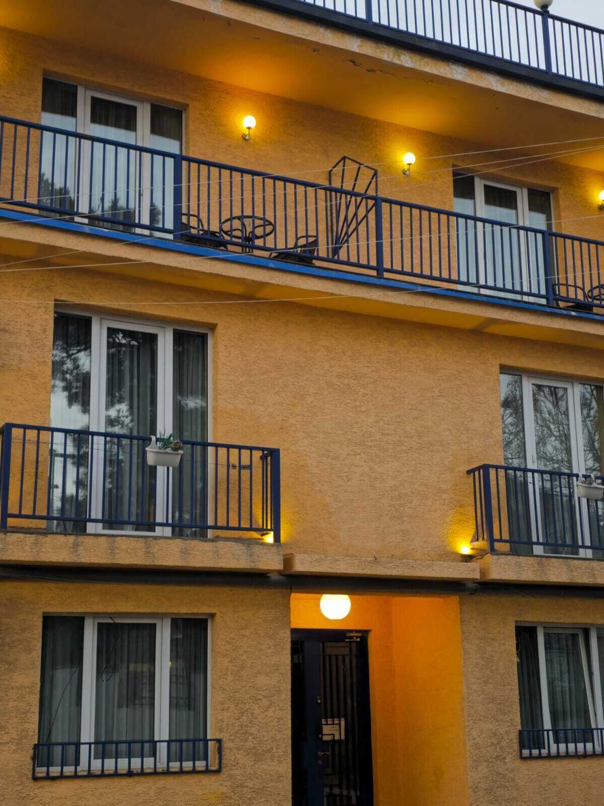 Un immeuble à plusieurs étages doté de balcons, chacun ayant une petite table et des chaises.