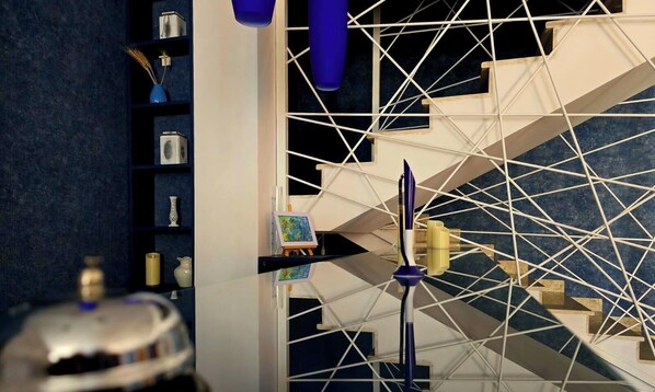 A modern interior with a geometric staircase, a small easel with a painting, and a reflective floor. - Hotel Nutsa in old Tbilisi (Tbilisi)