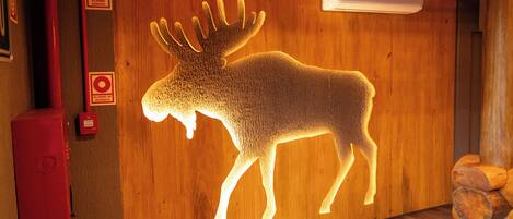 A wooden wall with a moose silhouette, a fire alarm, and an air conditioning unit.
