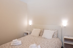A hotel room with a bed, two bedside tables, and a nightstand. - Bligny suite, Comfort and Style in the Historic Center (torino)