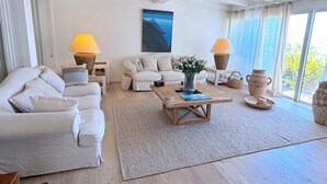 A spacious living room with a large window, a sofa set, a coffee table, and decorative vases. - Villa Paomia (cargèse)