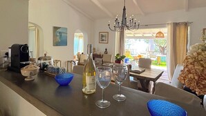 A kitchen with a dining area, a chandelier, and a view of the outdoors. - Villa Paomia (cargèse)