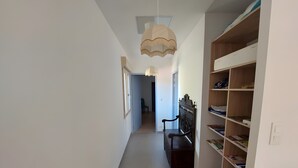 A hallway with a wooden bench, a bookshelf, and a ceiling light fixture.