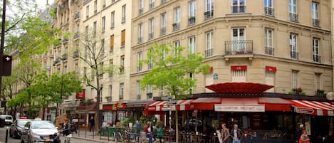A street view with a cafe named 'COMPTOIR BROCHANT' with outdoor seating, a building with multiple stories, and a crosswalk.