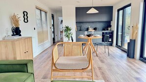 Een moderne woonkamer met een eethoek, een keuken en een groot raam.