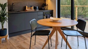 Een moderne keuken met donkere kastjes, een houten eettafel en stoelen.