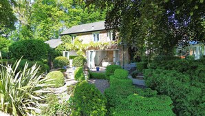 Ein Haus mit einem gepflegten Garten, einer sichtbaren Treppe zum Eingang und einem klaren Blick auf den Eingangsbereich.