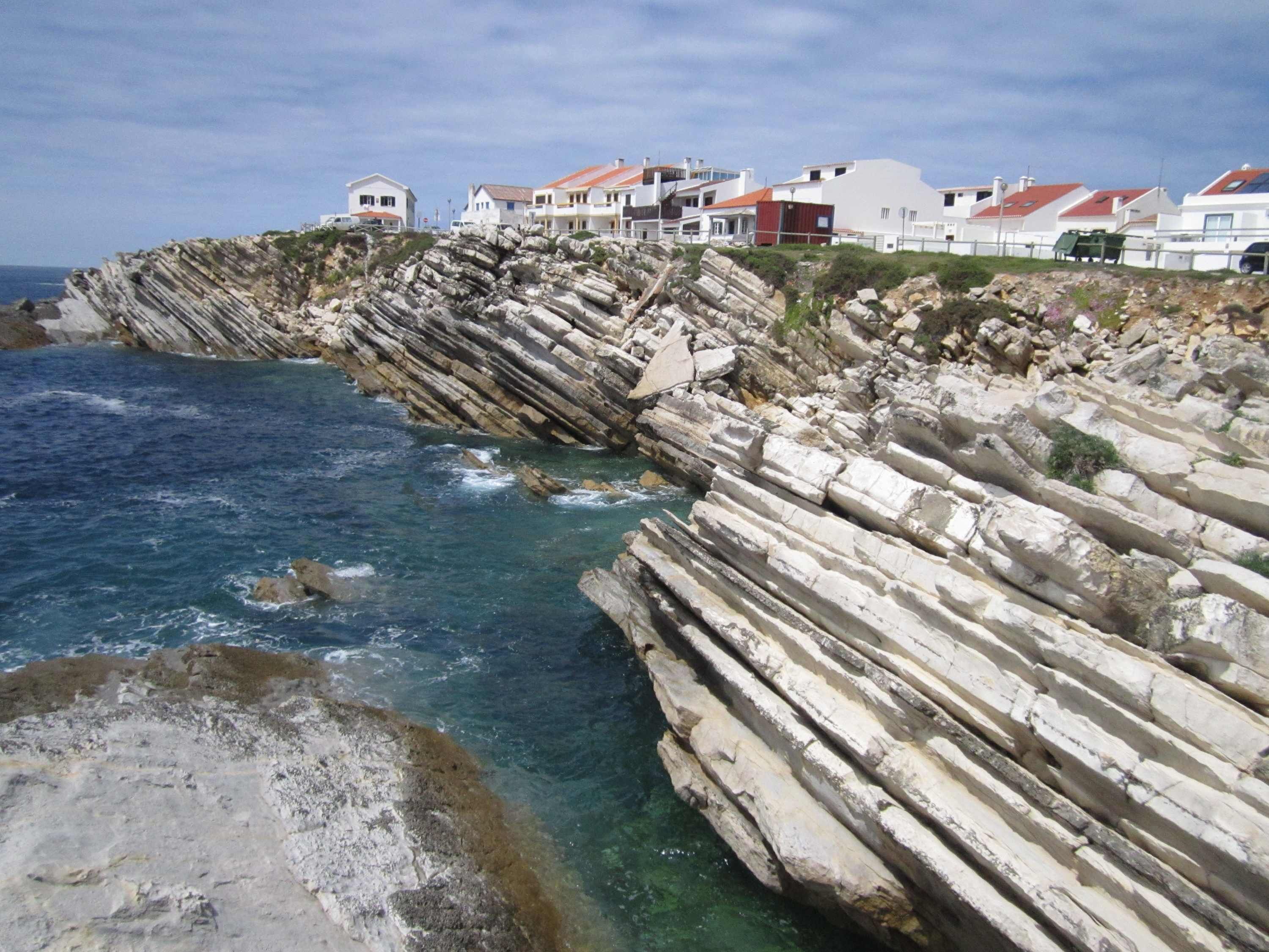 Una zona costera con acantilados rocosos y casas con tejados rojos.