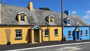 Une rangée de maisons jaunes et bleues, chacune présentant un style architectural distinct, notamment des toits à pignon et de petites fenêtres.