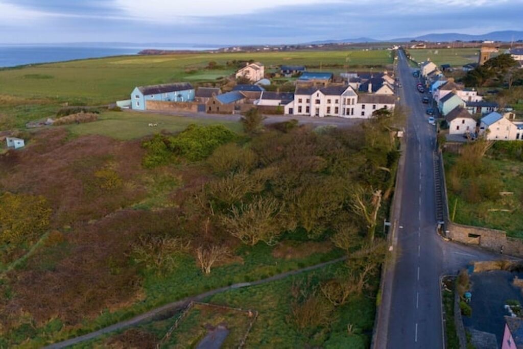 A coastal village with a main road, houses, and a large building.