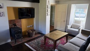 Un salon avec une cheminée, un canapé, une table basse et un téléviseur fixé au mur.