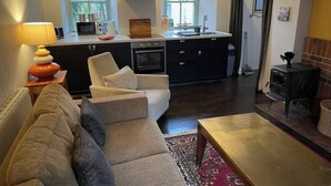 Un espace de vie compact comprenant un canapé, une petite table basse et un coin cuisine équipé d’un four à micro-ondes, d’un four et d’une cuisinière.